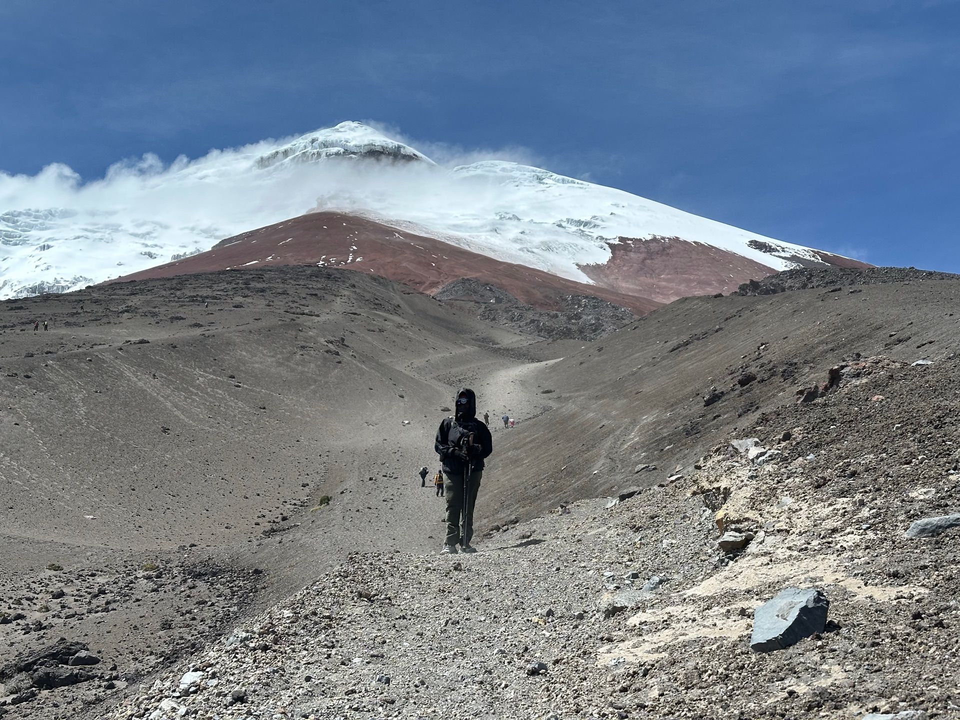 A trekker acclimatizing high on Cotopaxi's volcanic sand, with the summit glacier above